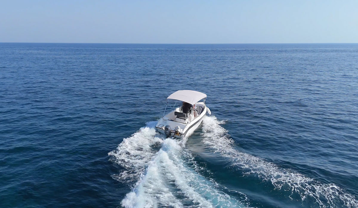 Private boat speeding across the Aegean Sea in Santorini – license-free rental experience