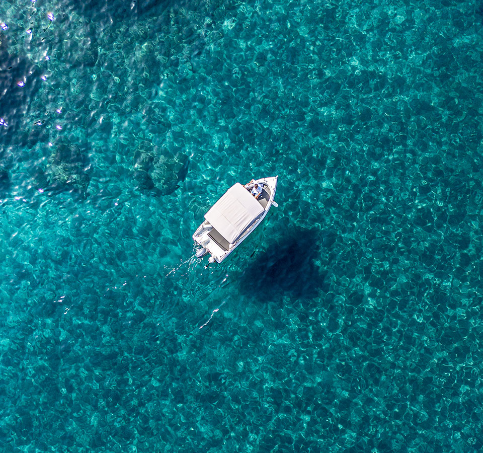 Aerial view of a private boat on clear blue water during a romantic boat proposal in Santorini